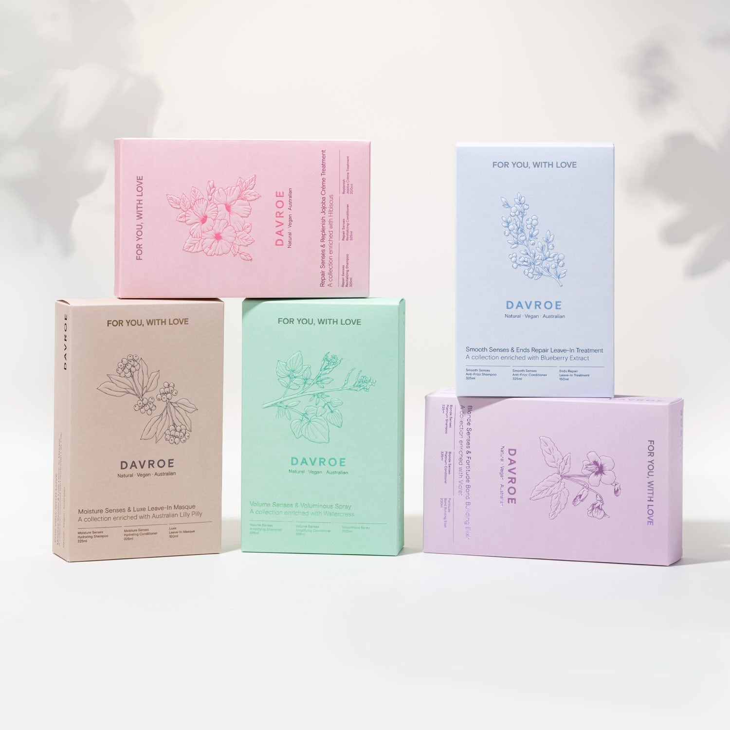 Fem pastellfargede DAVROE gavesett med teksten ‘For you, with love’, stablet i ulike høyder mot lys bakgrunn