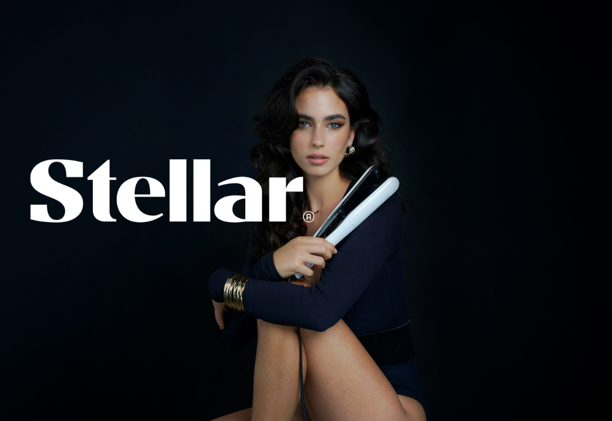 Kvinne med mørkt, bølgete hår sitter mot mørk bakgrunn og holder en hvit Stellar® hårrettetang, med stor Stellar-logo til venstre i bildet.